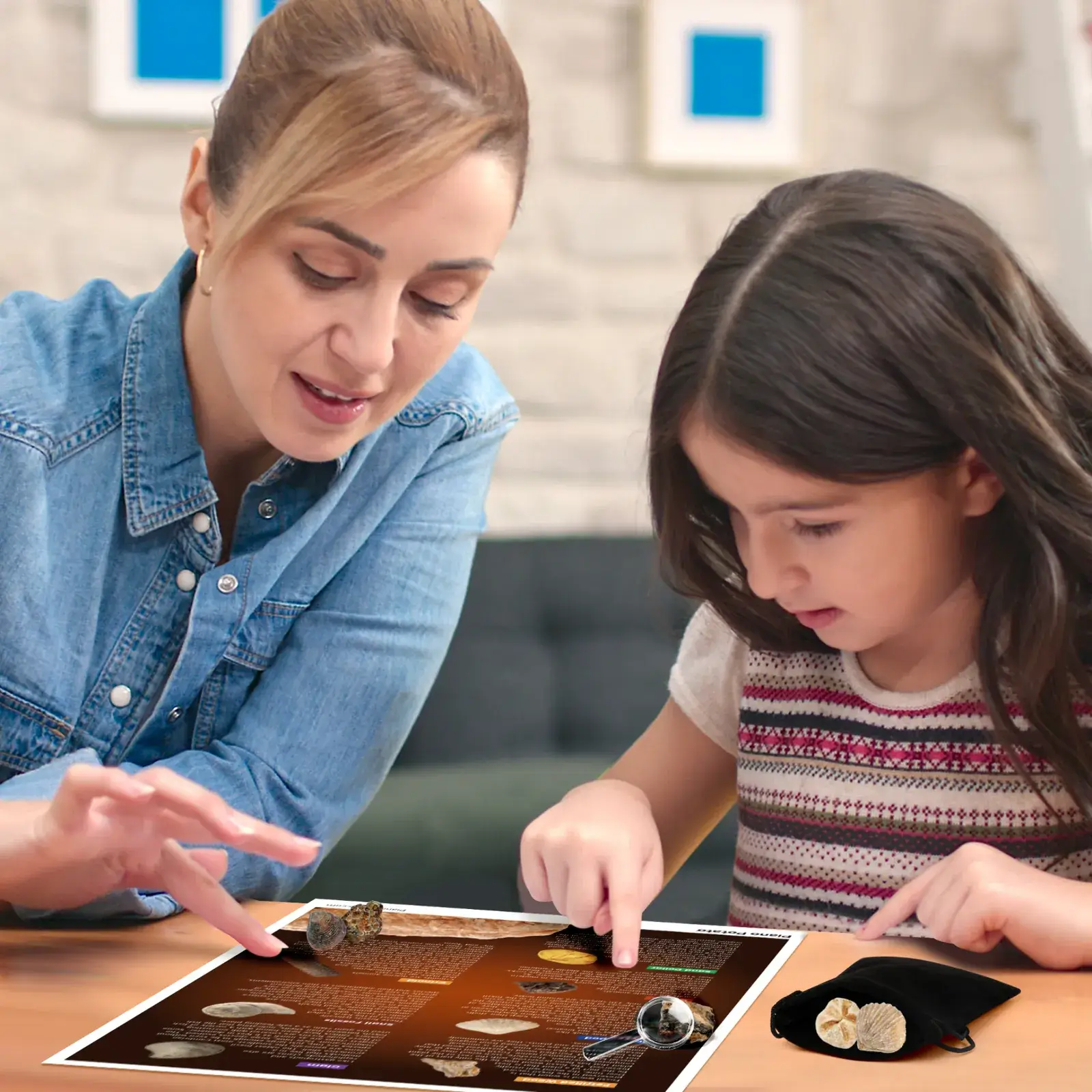 Child and adult examining fossil specimens with a magnifier and identification guide