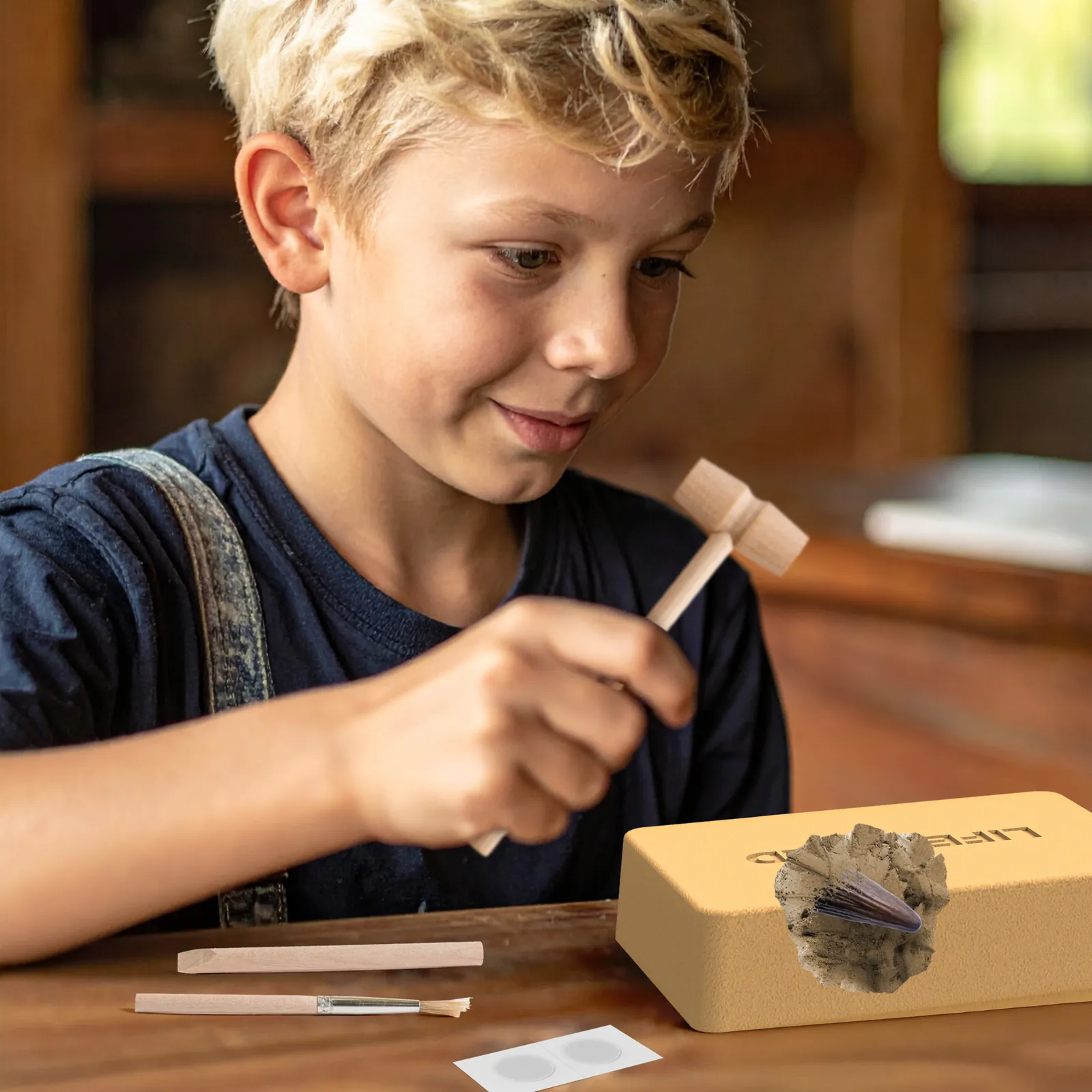 Child using the wooden hammer and chisel to excavate the Ankylosaurus spine replica